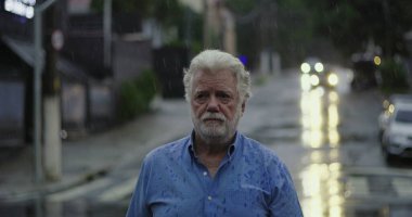 Boş şehir sokaklarında yağmurda tek başına duran yaşlı adam, duygusal olarak büyük bir üzüntü ve istifanın ifadesidir.