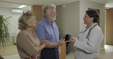 Sağlık haberlerini cesaretlendirdikten sonra klinikteki kadın doktora minnettarlık ve rahatlama gösteriyorlar.