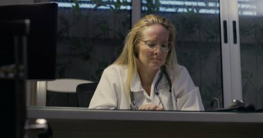 Kadın doktor umutsuzca başını eğiyor. Gece klinikte şiddetli yorgunluk belirtileri gösteriyor.