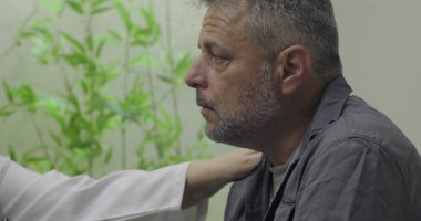 Muayene sırasında zor teşhislere tepki veren orta yaşlı erkek hastaların yakın çekimleri, klinik ortamlarda doktor tarafından desteklenirken duygusal tepkiler