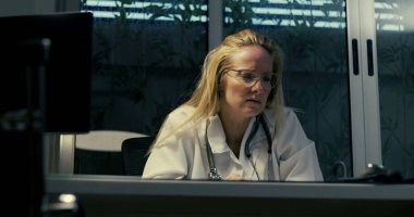 Gece vardiyası sırasında zor durumdaki kadın doktor, yoğun duygusal baskıyla karşı karşıya klinik ortamda otururken, ezici iş yükü ile boğuşurken,