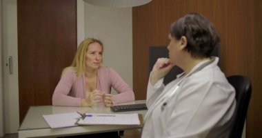 Klinikteki masadaki düşünceli tartışmalar sırasında doktorlara sağlık sorunlarını açıklayan orta yaşlı bir hasta.