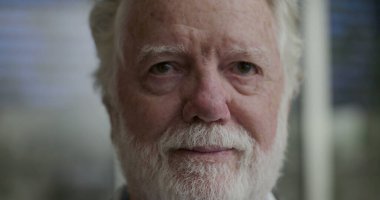 Beyaz Sakallı ve Düşünceli İfadesiyle Yaşlı Adam 'ın Yakın Çekim Portresi Kapalı Kapılar Arkaplanda Görüntü Bulanıklığıyla Doğrudan Kameraya Bakıyor