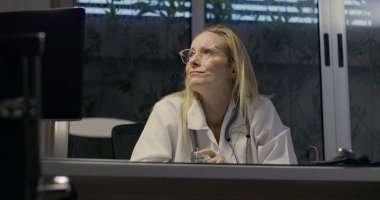 Kadın doktor umutsuzca başını eğiyor. Gece klinikte şiddetli yorgunluk belirtileri gösteriyor.