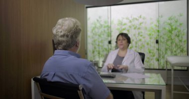 Modern klinikteki yaşlı erkek hastalarla test sonuçlarını tartışan doktor, berraklık, empati ve hasta odaklı iletişimi vurgulayan profesyonel sağlık danışmanlığı