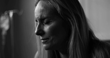 Tıp bürosundaki umut verici bir ifadeyle siyah beyaz kadın portresi. Damlalar görünür, duygusal derinlik ve sessizlik aktarıyor.