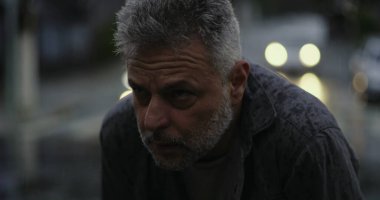 Yukarı bakan orta yaşlı bir adam, yağmurda ellerini kaldırmış, duygusal sorgulama ya da ruhani bir katman.