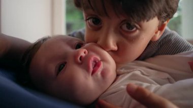 Ağabeyim bebeği yoğun bir şekilde öpüyor, sevecen ama ezici bir kardeş anı, çocukluk bağı, yakınlık, aile sevgisi, koruyucu kucaklama, duygusal bağ..