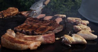 Sulu kaburgalar, sosisler ve kızgın ızgarada kızaran tavuk kanatları et yalarken yüksek hızlı kamerayla süper yavaş çekimde yakalanır.