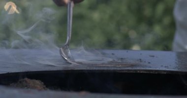 Kaşık, ızgaranın sıcak yüzeyine yemek pişirmeye başlarken yağ yayar. Isıtılmış metal tabaklardan yükselen duman...