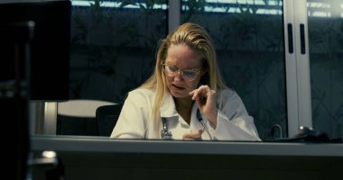 Gece vardiyası sırasında zor durumdaki kadın doktor, yoğun duygusal baskıyla karşı karşıya klinik ortamda otururken, ezici iş yükü ile boğuşurken,