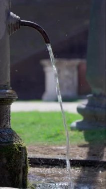 Sabit akıntıda akan suyun olduğu kamu çeşmesinin yakın çekimi, tarihi taş ayrıntıları ve ferahlatıcı açık hava atmosferi