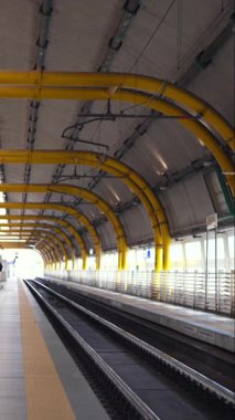 Boş modern tren istasyonu platformu. Parlak sarı boruları ve temiz rayları var.