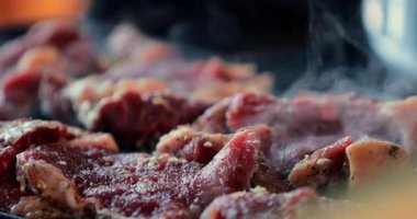 Pişirme işlemi başlarken taze et yüzeyinden yükselen yağlı mermer ve aromatik dumanla ızgaranın buharlı yakın çekimi.