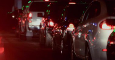 Kırmızı fren lambaları ve dağınık yeşil yansımalarla aydınlatılan uzun sıra arabalarla gece trafiği sıkışıklığı, yavaş hareket ya da yakın zamanda ışık değişikliğine işaret ediyor.