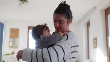 Anne bebeğini kucağında tutarken acı içinde kıvranıyor. Neşeli ama rahatsız edici bir aile etkileşimi sırasında evde rahat bir hayat sürüyor.