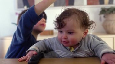 Ağabeyin bebek kardeşinin saçlarını yemek masasında nazik bir oyunculukla okşaması, her gün aile içi etkileşim, sevgi, neşe ve özgün kardeş bağı.