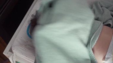 Bebek havluya sarılı bir şekilde masasını değiştiriyor, neşeyle gülümsüyor, aile içinde mutluluk, şefkat ve çocukluk ifadesi.