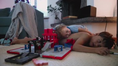 Çocuk oturma odasında oyuncak garajı, kardeş bağı konsepti, çocukluk enerjisi ve aile hayatı ile oyun zamanı sırtüstü uzanırken yerde yatıyor.