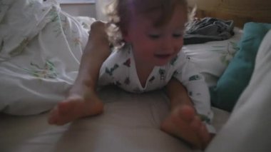 Bebek, ağabeyi üzerinde tırmanırken sabahları yatakta oynuyor, kardeş sevgisi, kaygısız oyun, aile yakınlığı ve evde neşeli çocukluk eğlencesi konsepti.