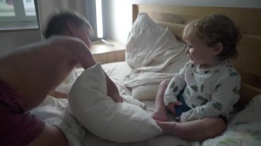 İki genç kardeş, rahat bir yatak odasında yatakta yuvarlanırken güreşiyor ve gülüyor. Neşeli çocukluk bağı, kaygısız aile hayatı ve neşeli birliktelik kavramı.