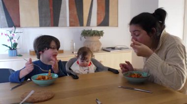 Anne yemek masasında çocuklarla yemek yiyor, aile yemekleri yiyor, ebeveynlik, iletişim ve günlük yaşam tarzını paylaşılan yiyeceklerin etrafında gösteriyor..