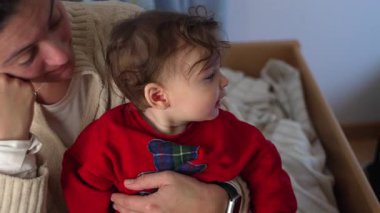 Büyük kardeş küçük kardeşle kucaklaşırken, anne ikisini de kucaklıyor, neşeli bir aile anı, sevgi, bağ ve birliktelik.