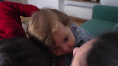 Anne ve ablasının arasına kurulmuş küçük bir çocuk sıcak bir aile sahnesinde kanepede sevgi dolu bir kucaklaşma sırasında.