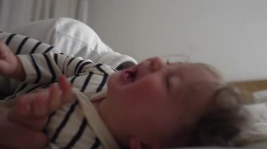 Gıdıklanırken gözleri kapalı gülen bebek, saf mutluluk, yakınlık ve anne ile sevgi dolu bir etkileşim gösteren neşeli aile oyun zamanı..