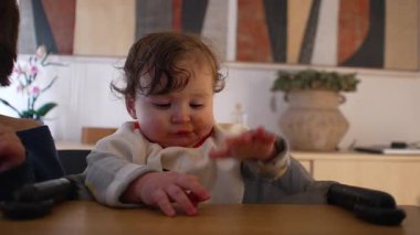 Bebeğin ebeveyn tarafından sunulan makarnayı reddetmesi, onun yerine kamera dışı bir şeye uzanması, ebeveynlik mücadelesini, yürümeye başlayan meydan okumayı ve yemek zamanını gösterme anı