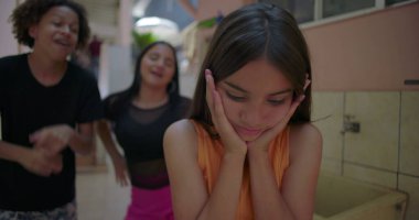 Kenar mahallelerdeki arkadaşlar tarafından dalga geçilirken genç kız, zorbalık, arkadaş baskısı ve duygusal izolasyon konularını vurguluyor.