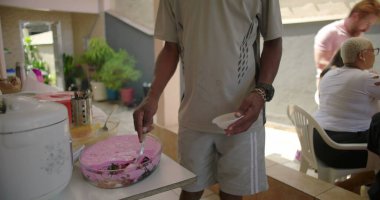 Afro-Amerikan Adam, barbekü partisinde kendine tatlı ikram ediyor. Bağ gösterme, yemek paylaşma ve aile ve arkadaşlar arasında öğle yemeği sonrası rahatlama.