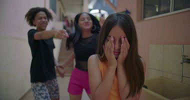 Kenar mahallelerdeki arkadaşlar tarafından dalga geçilirken genç kız, zorbalık, arkadaş baskısı ve duygusal izolasyon konularını vurguluyor.