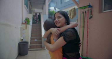 Banliyöde sarılıp gülümseyen iki Latin Latin kız, dostluğu ve çok kültürlü kimliği temsil eden neşeli ve sevecen bir an.