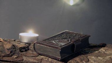 Eski ahşap masa, yanan mum ve kitap.