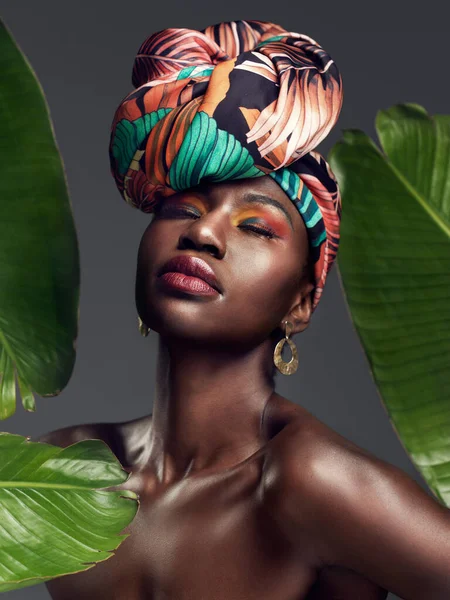 時には最も単純なアクセサリーは大声で話す 緑豊かな背景に伝統的なアフリカの頭のラップを身に着けている美しい若い女性のスタジオショット — ストック写真