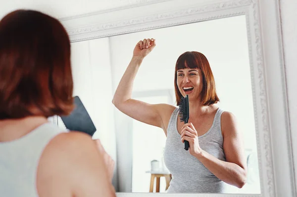 Good hair brings out your inner star. an attractive young woman holding a hairbrush and singing in her bathroom at home