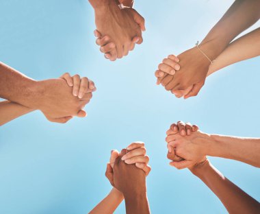 Eller, dayanışma ve el ele tutuşmalar, destek ve işbirliği, mavi gökyüzü arka planına sahip ortaklık ve çeşitlilik. Takım çalışması, birlik ve bir grup insan, takım oluşturma ve güven ile topluluk oluşturma