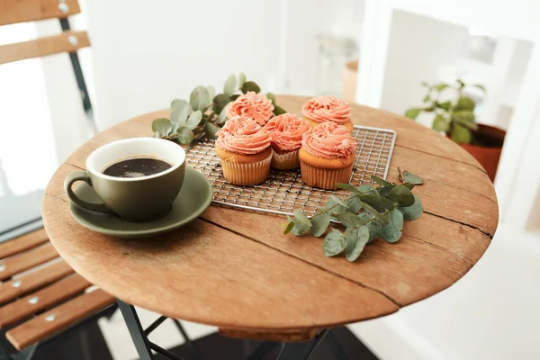 Coffee and cupcakes are the best remedies for anything. freshly baked cupcakes on a metal tray and a cup of coffee on a table indoors