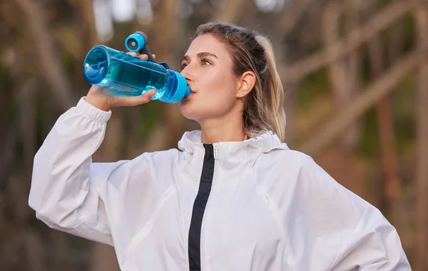Fitness, health and runner woman with water bottle for hydration break on cardio run in nature. Training, running and healthy lifestyle of athlete girl with drink for workout, exercise and sport