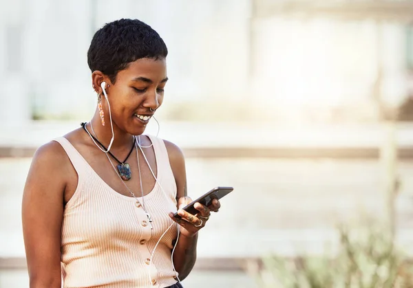 Black woman, smile and phone in social media with headphones in joy for 5G  connection in the outdoors. Happy African American female student smiling  for technology and internet on mobile smartphone