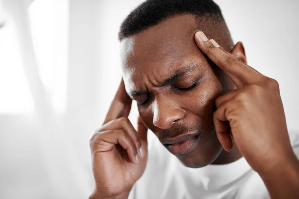 stock image I cant think with this headache. a young man suffering from a headache at home