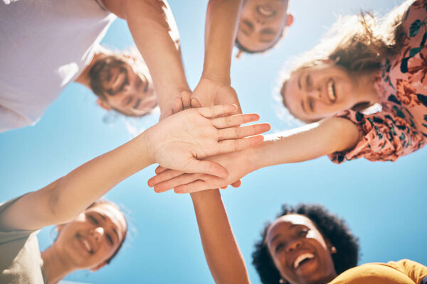 Hands, friends or support in community collaboration, trust or motivation for goals, success or solidarity. Low angle, huddle or circle of smile or happy people, men or women in diversity celebration.