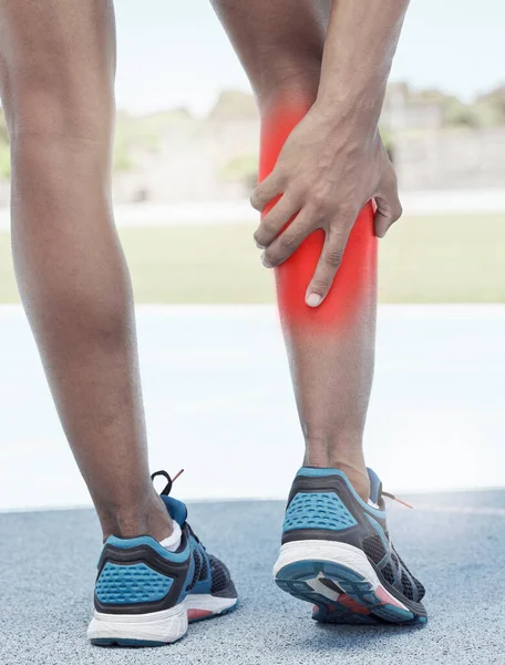 Runner, calf pain and leg injury accident during fitness running exercise in athletic shoes outside. Sports man, muscle strain and calf during marathon cardio training workout on track field.