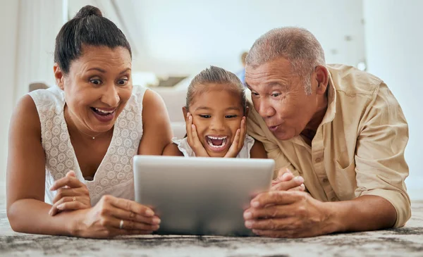 Relax, digital tablet and family on floor in living room, wow and happy with online cartoon or animation in Mexico. Happy family, grandparents and girl bond, watch and enjoy internet fun together.