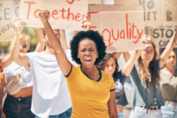 Протест, толпа людей и черная женщина на улице, кулак в воздухе маршируют за равенство, права человека и свободу. Разнообразие, протесты и женщина, кричащая о справедливости в городе с картонными знаками.