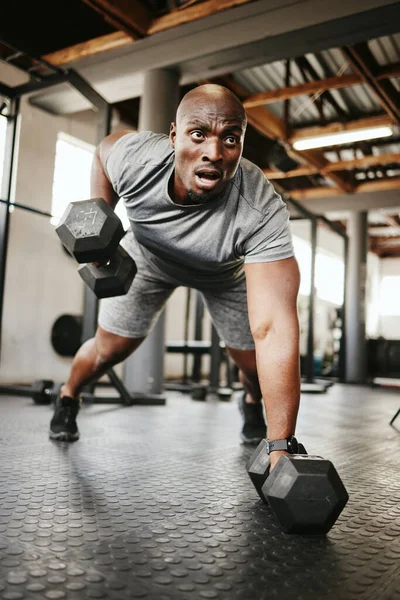 Fitness, gym and black man doing a workout with weights for strength, wellness and training. Bodybuilder, sports and strong African athlete doing push up exercise in a sport, health and active studio.