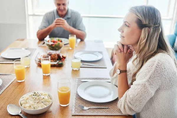 Woman, thinking at the dinner table in gratitude for food, family and home. Female sitting in thought with father in hope, spiritual and religion for grateful thanksgiving meal together.
