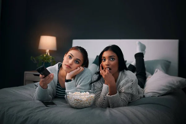 代わりに映画をオンラインで借りるべきだ 2人の若い女性が家で映画を見ながらポップコーンを食べる — ストック写真