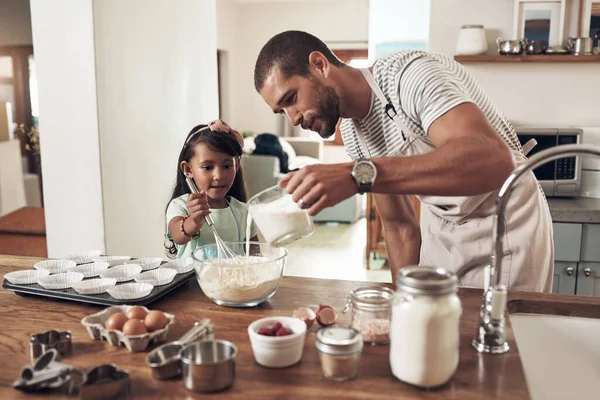 Baking is cheaper than therapy. a father teaching his daughter how to bake in the kitchen at home